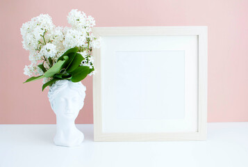white replica of plaster statue of head of David and white lilac on a pink background. Flower arrangement with a plaster copy of an antique statue. spring season. Creative concept of minimalistic art