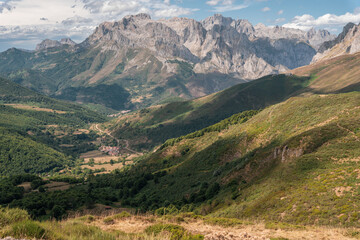 Obraz premium view of a beautiful natural landscape with lots of trees and vegetation with a small village in the middle and the Picos de Europa in the background.