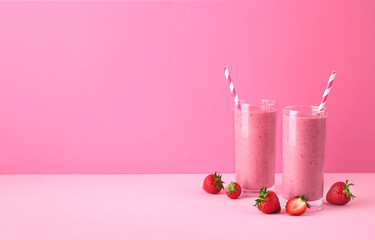 Two glasses of strawberry smoothie or milkshake on pink background