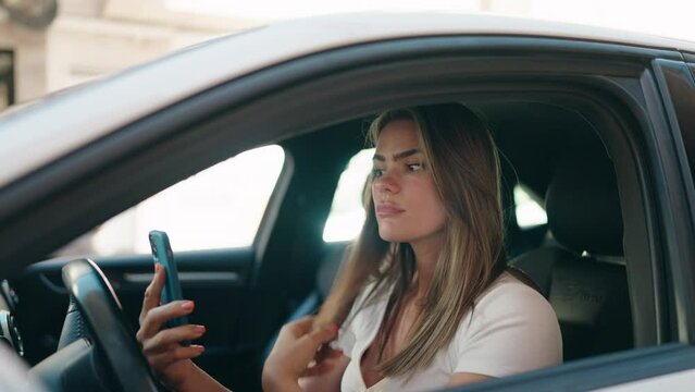 Young woman using smartphone sitting on car at street