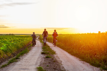 mother and her children ride bicycles in the countryside at sunset. Sports family riding bicycles. happy family concept