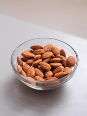 Almonds in glass bowl on kitchen counter, healthy food for diet.