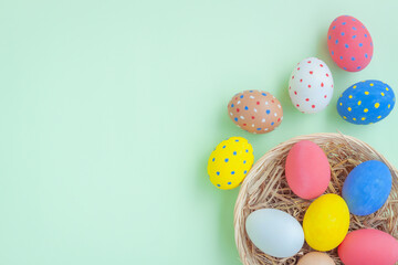Colorful eggs in a basket on green background