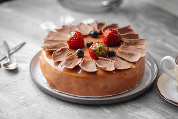 Closeup on caramel glazed cake with berries and cup of tea