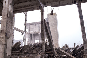 Ruins of concrete fragments and concrete beams against the background of the remains of the...