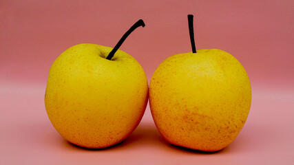 Two pears with stem on pink background