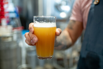 Close shot of a man holding glass of beer in brewery