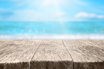 Empty wood table over blurred blue sea and beach background in sunny summer day. Background with copy space for product display