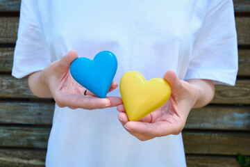 Blue and yellow heart in the hands of a girl on a light background. Independence of Ukraine. Flag. Ukraine love concept