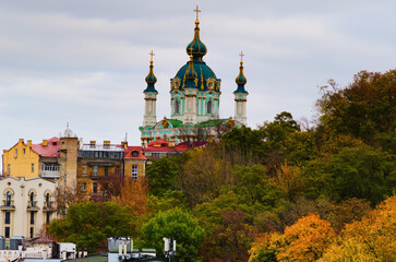 Scenic autumn cityscape of Kyiv. Saint Andrew's Church and ancient buildings of Andrew's Descent (Andriyivsky uzviz, Podil neighborhood). Famous touristic place and romantic travel destination