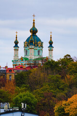 Fototapeta na wymiar Picturesque autumn cityscape of Kyiv. Saint Andrew's Church and ancient buildings of Andrew's Descent (Andriyivsky uzviz, Podil neighborhood). Famous touristic place and romantic travel destination