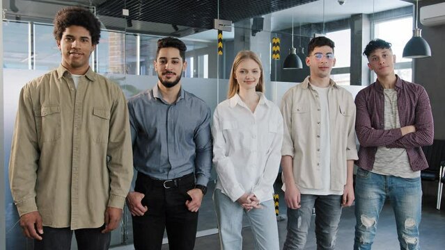 Young happy employees stand in row looking at camera smiling diverse different colleagues posing in office five confident professional business people corporate staff group team teamwork cooperation
