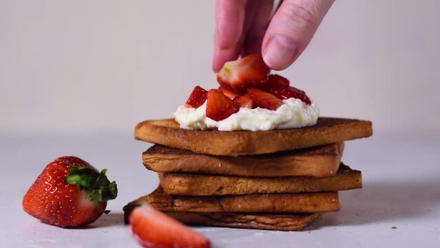 Serving bruschetta with strawberry and stracciatella cheese on stack of toasted bread slices 