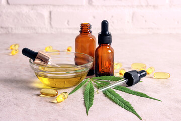 Marijuana and cannabis oil in a glass bottles, bowl, pills and capsules with green marijuana leaf.
