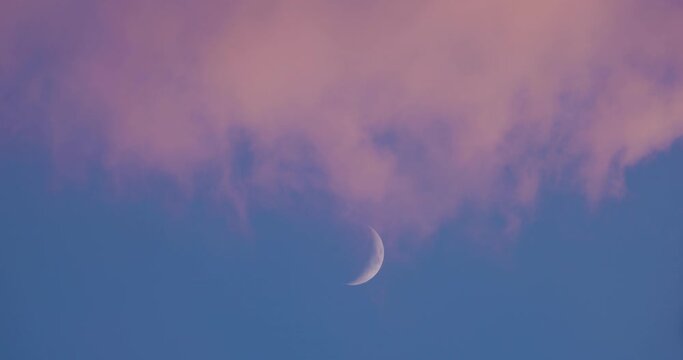 4k UHD of the full moon that sets crossing the clouds in the blue sky and disappears in the sky cleared by the light of dawn - sky with moon, background