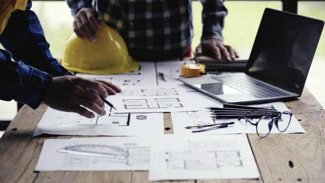 Engineers and architects discuss construction plans. Work on the blueprints on the desk in the architect's office, use the building plan. Design brainstorming, plan a successful development strategy.
