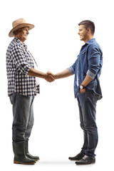 Full length profile shot of a mature farmer shaking hands with a young casual man