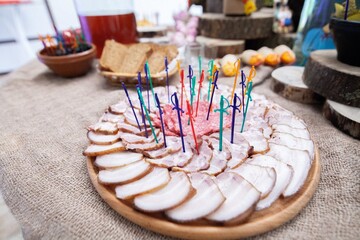 Sliced ​​bacon lies on a wooden stand. decorative swords stick out in bacon