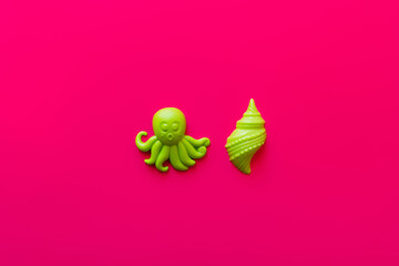 top view of green octopus and shellfish toys on pink background.