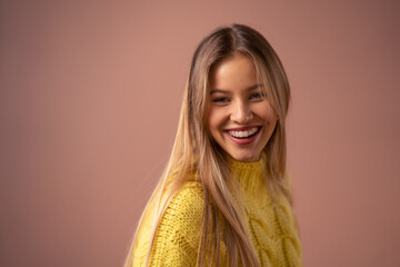 Fashion studio portrait of happy young blonde woman posing over pink background.