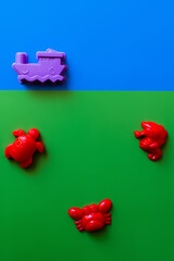 top view of red sea animals and purple ship toys on blue and green background.