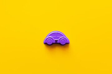 top view of purple plastic car on bright yellow background.