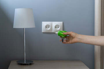 Woman hand plugs mosquito repellent into the socket before going to bed. Domestic electric raptor...