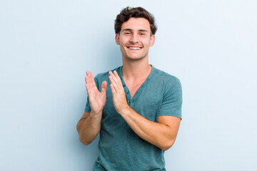 young handsome man feeling happy and successful, smiling and clapping hands, saying congratulations with an applause - obrazy, fototapety, plakaty