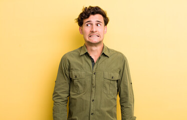 young handsome man looking worried, stressed, anxious and scared, panicking and clenching teeth