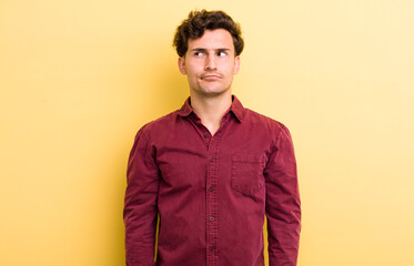 young handsome man looking puzzled and confused, wondering or trying to solve a problem or thinking