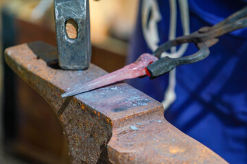 Blacksmith with red-hot iron at work