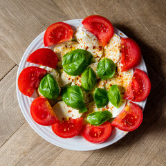 Tomato, basil, mozzarella Caprese salad with balsamic vinegar and olive oil. Top view, wood background