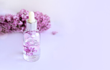 Obraz na płótnie Canvas Closeup of glass dropper bottle with pipette with serum and lilac flowers. Essential oil, natural beauty cosmetics, bio science and research, skin care concept. Macro. Front view, high angle shot