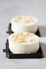 Tasty Round White Mini Cheesecake Decoreated with Almond Modern Dessert Minimalism Gray background Vertical