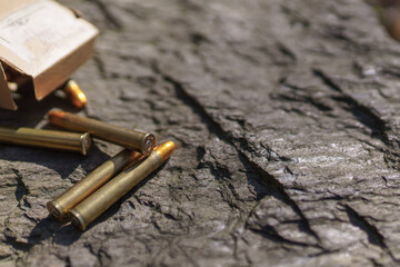 Rifle bullets and cartridges close-up on rock outdoors.