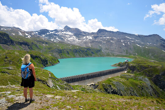 Hiker by the mountain lake Lac de Goillet, Aosta valley, Italy. Summer landscape in the Alps.