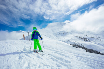 Fototapeta na wymiar Preteen handsome boy ski downhill on mountain slope