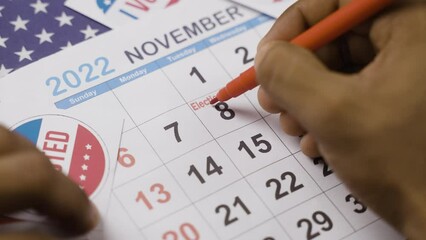 close up shot of hands marking November 8 as reminder for polling in 2022 US or american mediterm election.