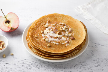 Apple pancakes with condensed milk and nuts on a light gray background, top view. Delicious homemade food