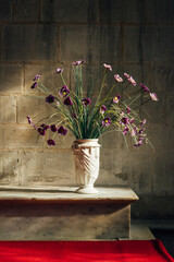 Un bouquet de fleurs dans un vase posé sur un autel dans une église. Un vase avec des fleurs...