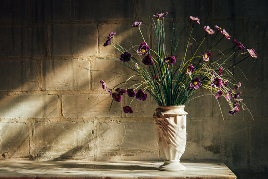 Un bouquet de fleurs dans un vase pos&eacute; sur un autel dans une &eacute;glise. Un vase avec des fleurs violettes et jaunes.