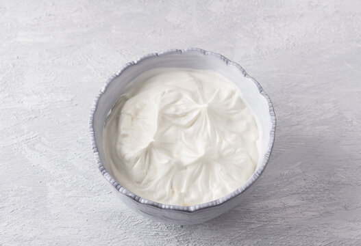 Gray bowl with whipped cream for cooking dessert "Pavlova" on a light gray background