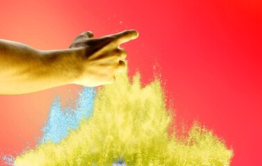 Hand and explosion of colored dust or sand, powder on gradient background with neon light. Trendy colors.