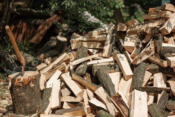 An ax sticks out in a deck. A stacked pile of chopped firewood for the stove. Agriculture