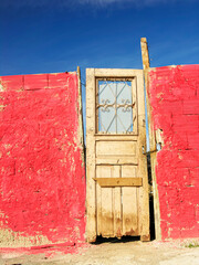 Door in dilapidated house. Red wall. Beautiful blue cloudless sky. Nice picture.