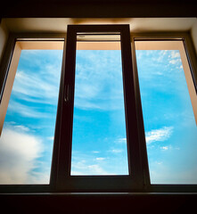 A window with a view of the sky and clouds. Sunny weather.