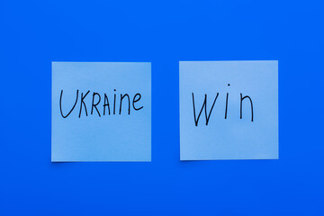 top view of ukraine win lettering on paper cards and blue background.
