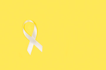 Lazo cinta blanca sobre un fondo amarillo liso y aislado. Vista superior y de cerca. Copy space