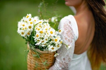 A middle-aged woman holds a large bouquet of daisies in her hands. Wildflowers for congratulations