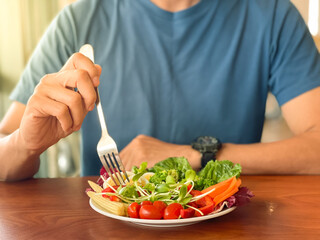 Man's hand scooping green salad. Healthy lifestyle and vegetarian vegan, Intermittent Fasting concept.